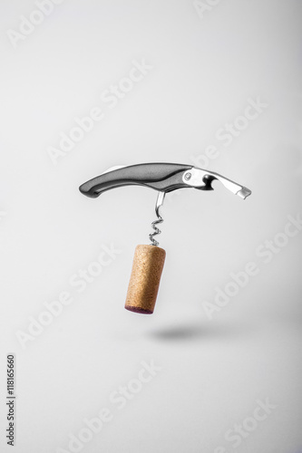Wine cork and bottle opener floating on white background