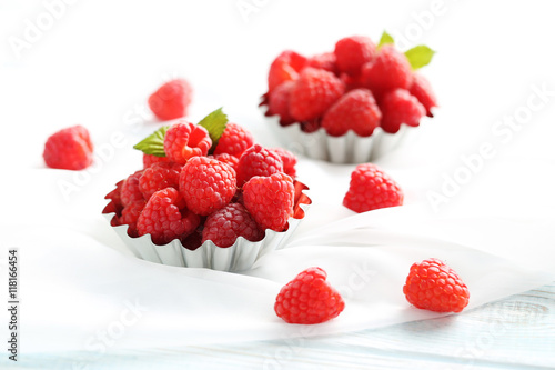 Red raspberries in bowl on a white wooden table