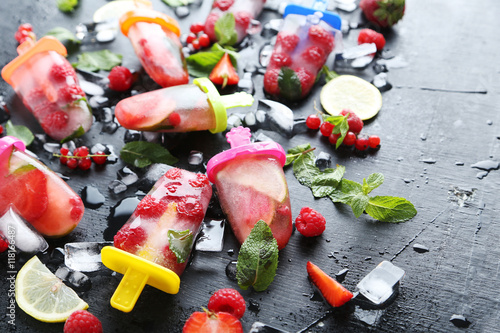 Popsicles with berries on black wooden table