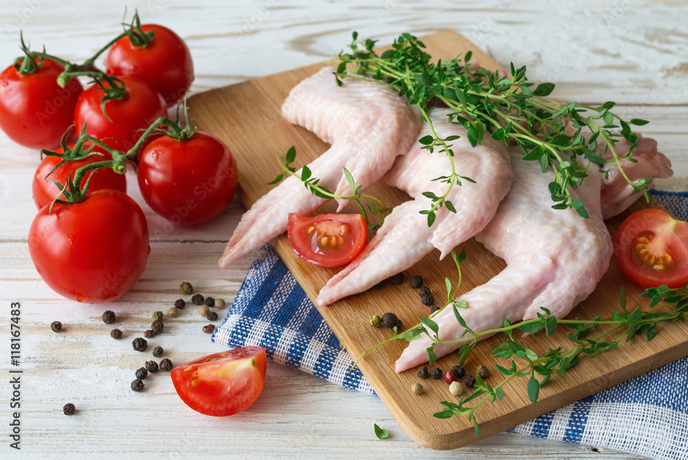 Raw chicken wings with thyme, chili, pepper and tomatoes Raw chicken wings with thyme, chili, pepper and tomatoes