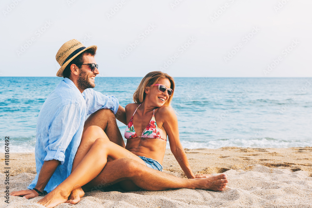 Fototapeta premium Young couple in love lying on the beach, enjoying 