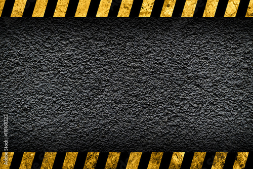 Grunge dark grey background with black and yellow warning stripes