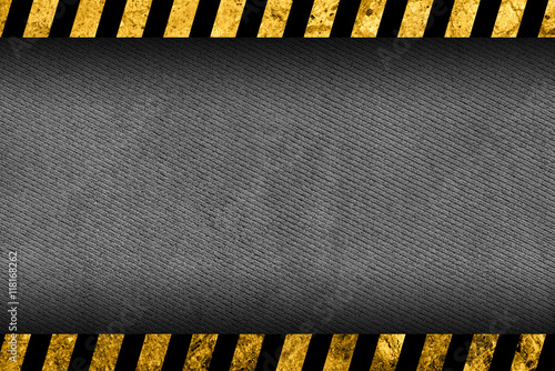 Grunge dark grey background with black and yellow warning stripes