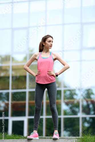 Young woman resting after run on building background