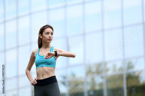 Young woman checking time after run on building background © Africa Studio