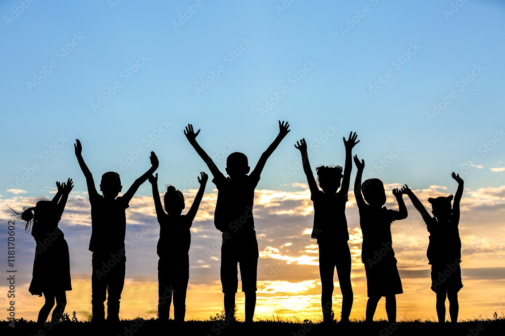 Happy kids silhouettes on sunset background