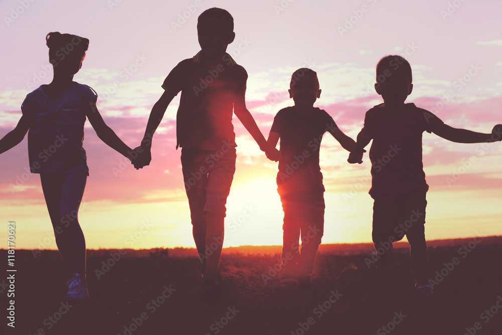 Fototapeta premium Happy kids silhouettes on sunset background
