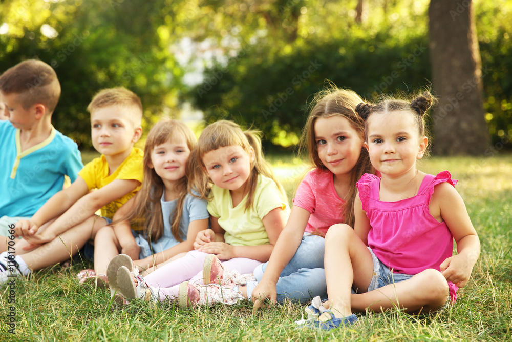 Fototapeta premium Happy kids sitting on grass in park