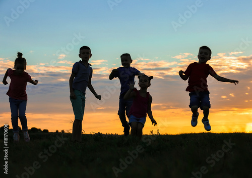 Happy kids silhouettes on sunset background © Africa Studio