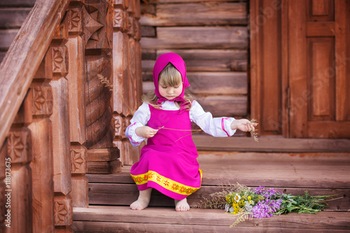 Masha on the porch of a wooden house with wildflowers