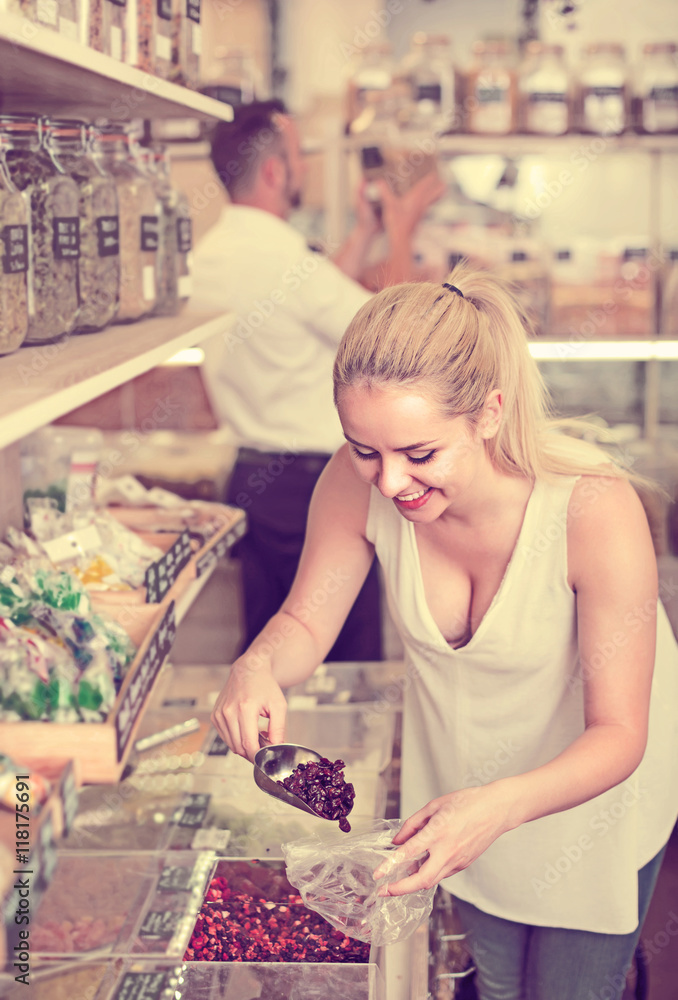 Fototapeta premium Woman picking dried fruits in store .