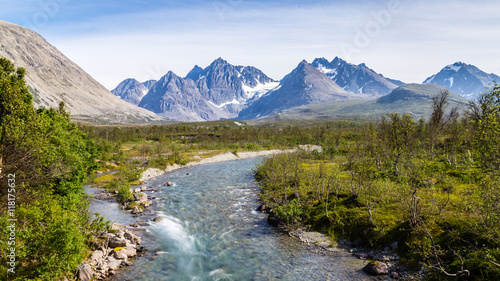 Scandinavian landscape with rapids in a river and a glacier in the background on the island Lyngen in Norway