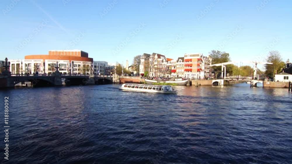 A typical amsterdam scene with touristic boats passing in a canal A typical amsterdam scene with touristic boats passing in a canal