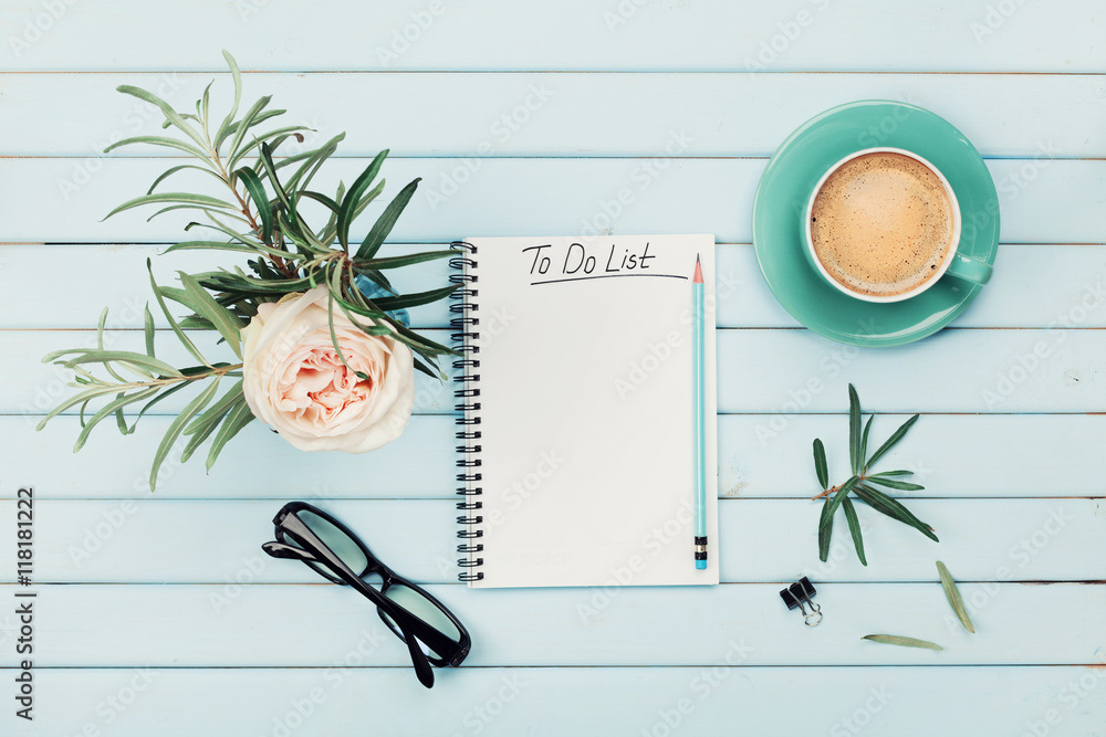 Φωτογραφία Morning coffee cup, notebook with to do list, pencil, eyeglasses and vintage rose flower in vase on blue rustic table from above