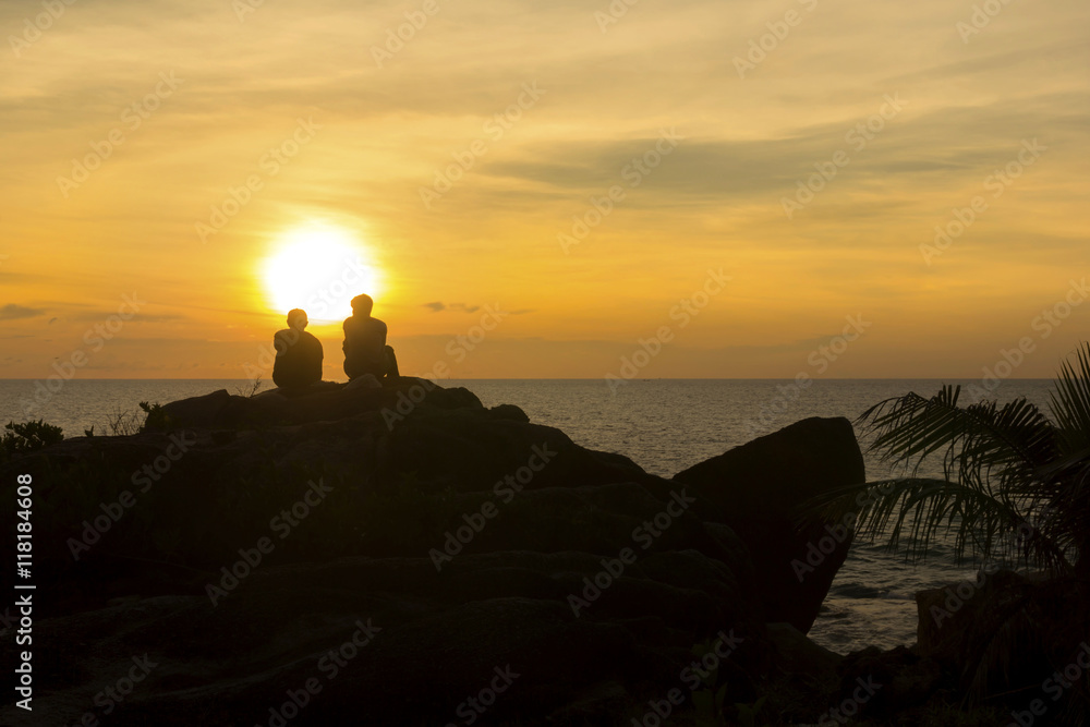 Silhouette two man on the rock and sunset