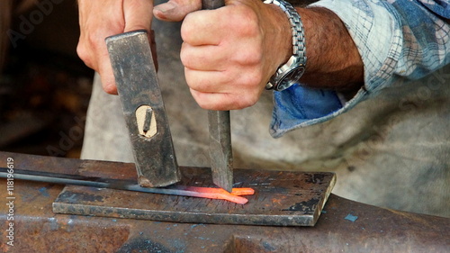 Schmied arbeitet mit Hammer und Meißel an glühendem Stahl (Nahaufnahme)