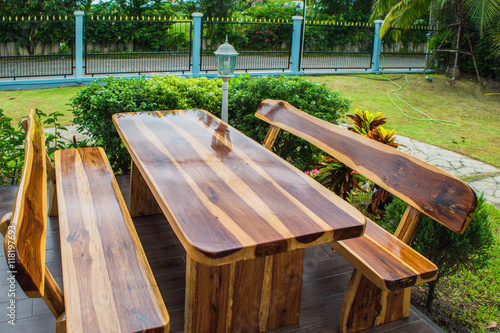 a wooden dining table set in lush garden setting © Aniruth