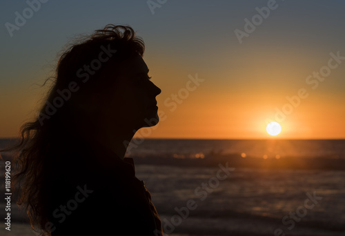 Silhouette profile of young female during sunset in San Diego pacific ocean beach, California