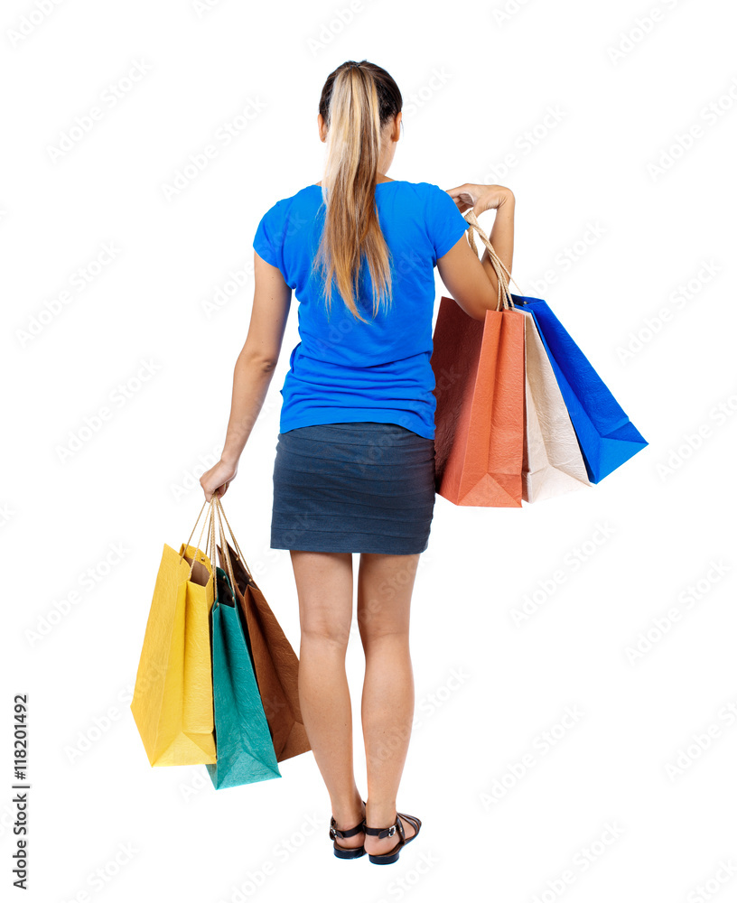 back view of woman with shopping bags. backside view of person.  Rear view people collection. Isolated over white background. girl in a short skirt and a blue shirt holding paper bags.