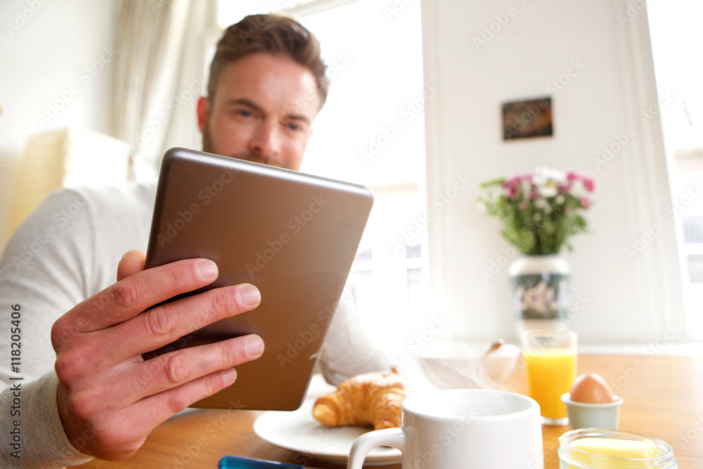 Older man holding tablet over breakfast Older man holding tablet over breakfast