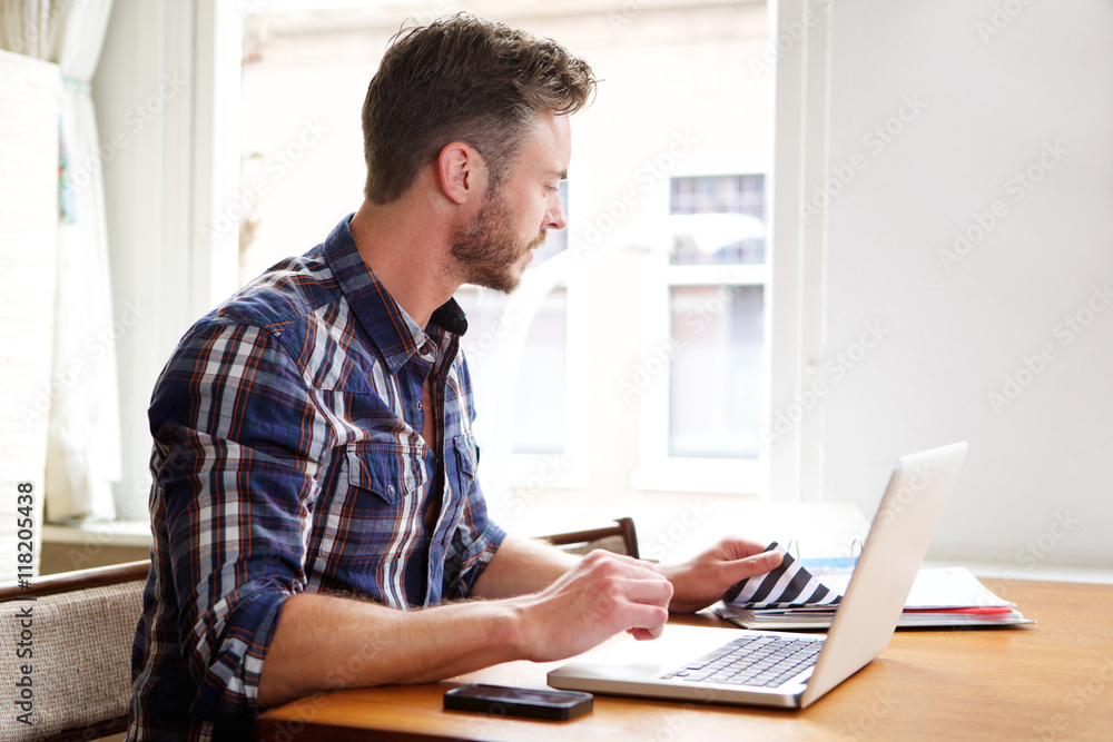 Older man working at desk with binder and laptop thinking Older man working at desk with binder and laptop thinking