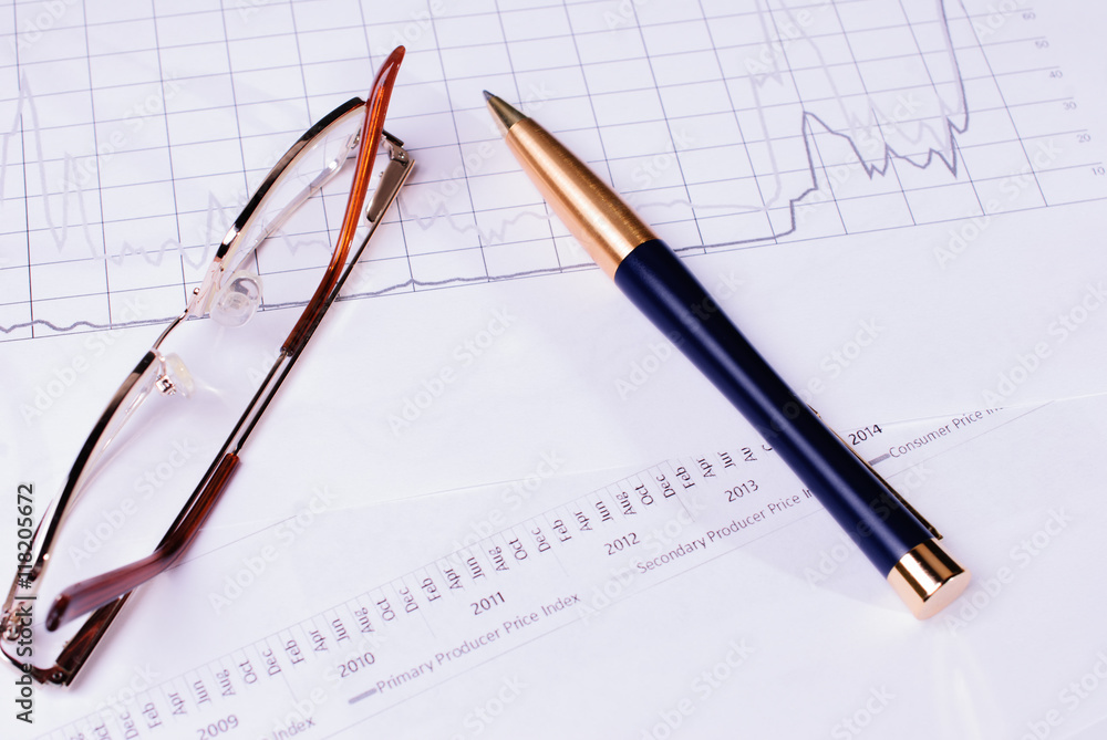 Business concept with Finance graphs, pen and glasses Business concept with Finance graphs, pen and glasses