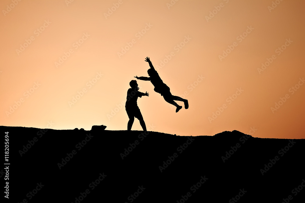 A silhouette of a guy catches his girl jumping on him with open arms A silhouette of a guy catches his girl jumping on him with open arms