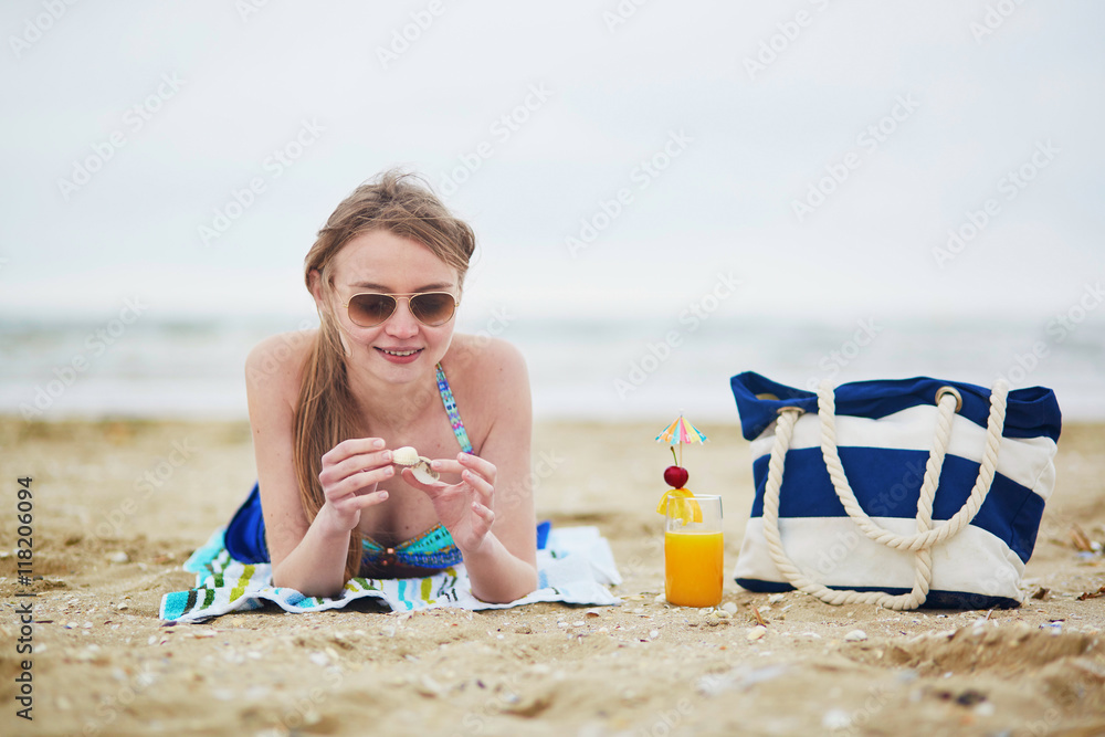 Woman relaxing and sunbathing on beach - obrazy, fototapety, plakaty 