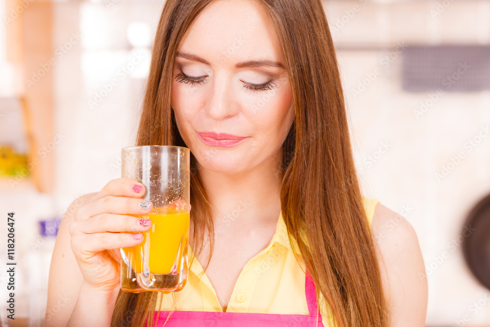 Woman in kitchen drinking fresh orange juice Woman in kitchen drinking fresh orange juice