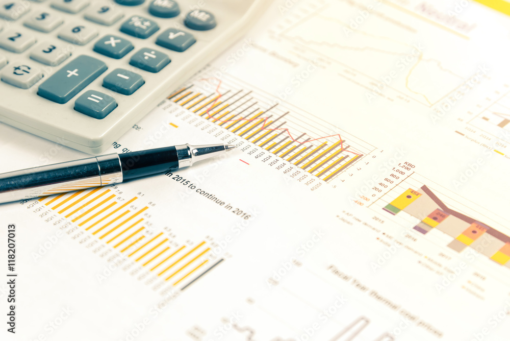 Close up of pen on financial documents with calculator in background. Business concept photo with sunlight filter. Close up of pen on financial documents with calculator in background. Business concept photo with sunlight filter.
