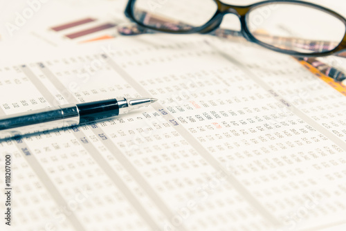 Close up of pen on financial documents with glasses in background.Business concept.