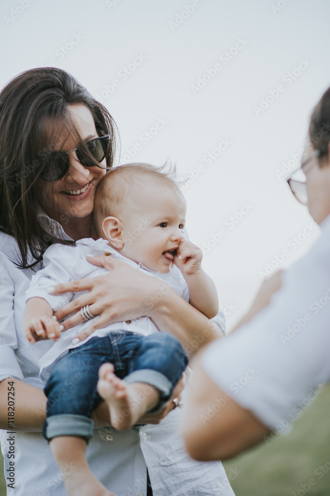 Happy young family having fun, bowl, rising up, piggyback ride their child in park on summer sunset Happy young family having fun, bowl, rising up, piggyback ride their child in park on summer sunset