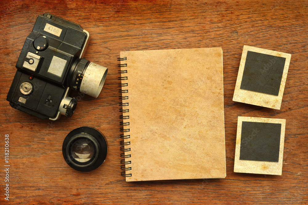 notebook with photo frames and camera on wooden background with sunlight vintage color