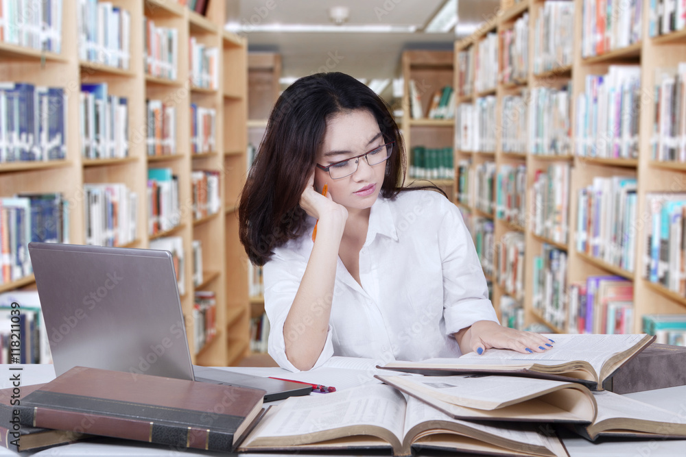 Clever female student reads books in library Clever female student reads books in library