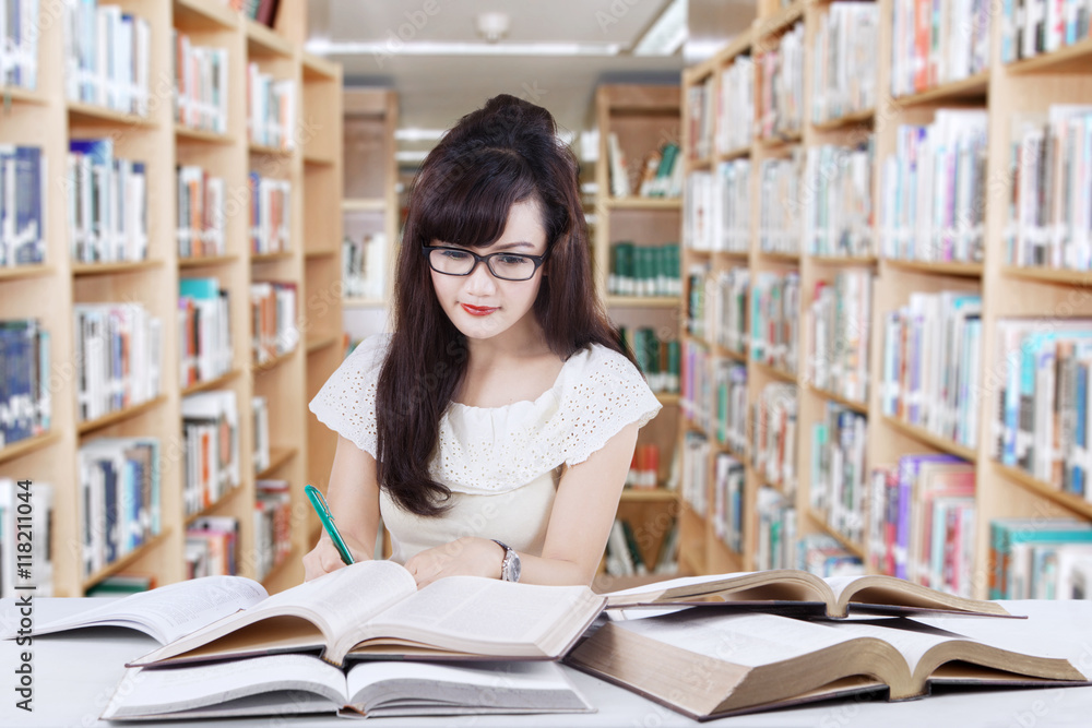 Clever learner doing school task in library Clever learner doing school task in library