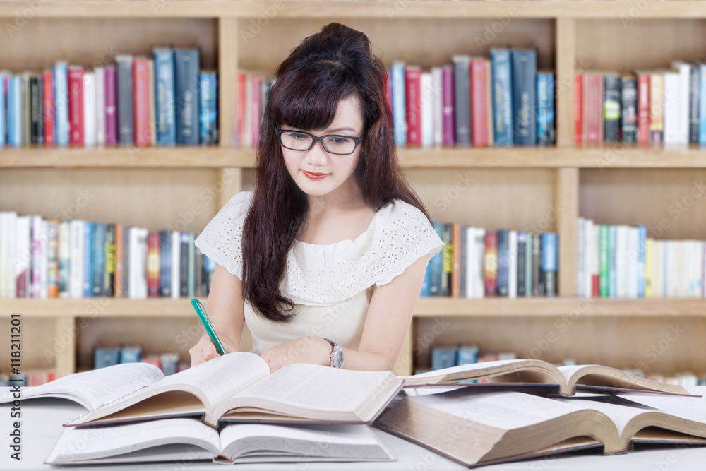 Female student writing in the library Female student writing in the library