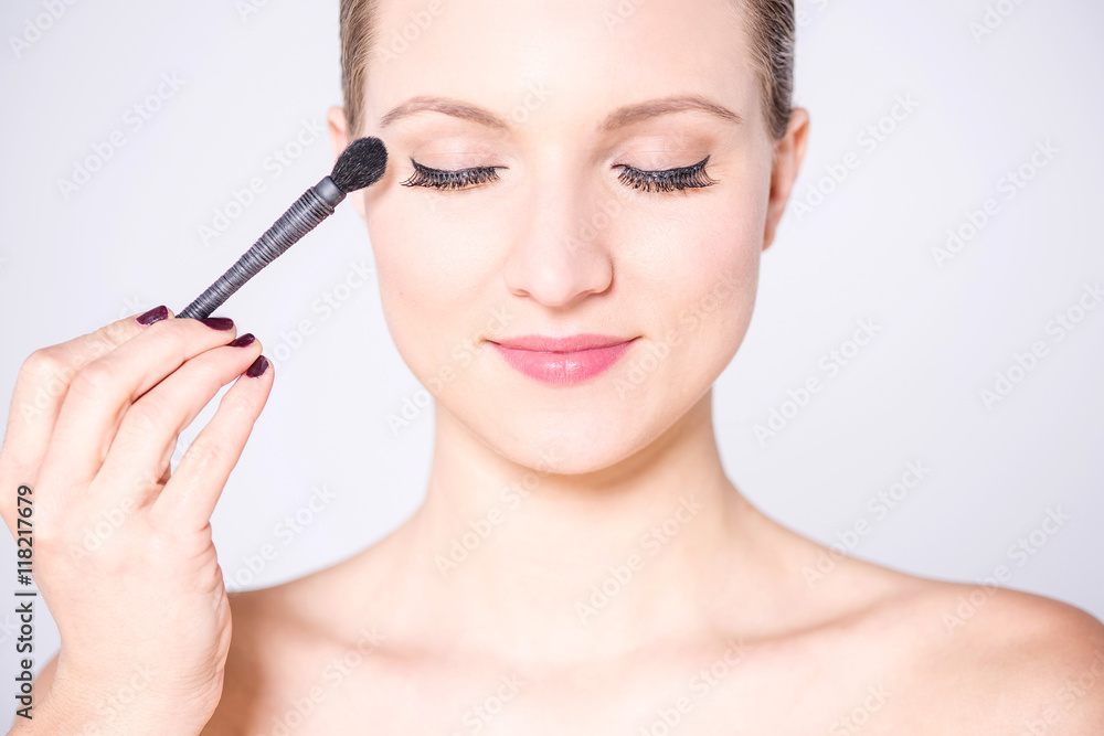 Young pretty woman applying make up