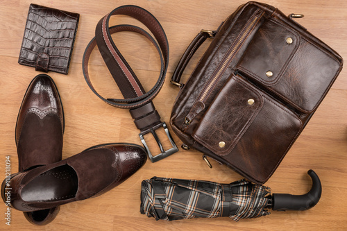 Classic brown shoes, briefcase, belt and umbrella on the wooden floor