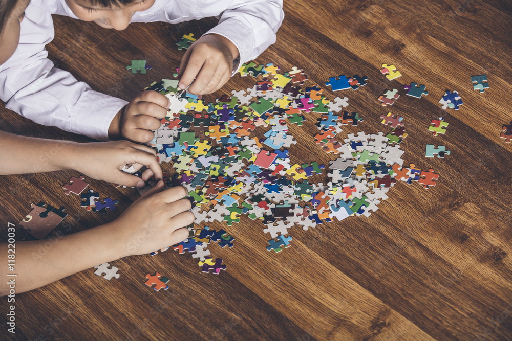 Happy boy and girl collect puzzle lying on the floor Happy boy and girl collect puzzle lying on the floor