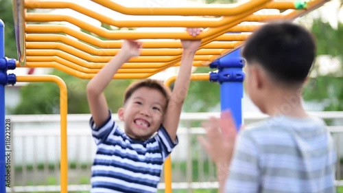 Two young asian boy hang the yellow bar by his hand to exercise at out door playground
