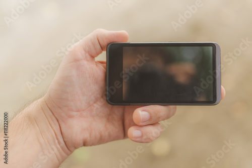 Male hand with mobile phone on the beach