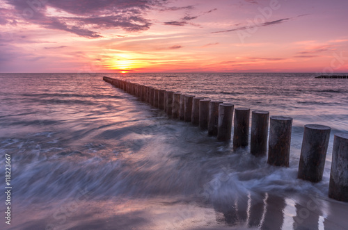 Colorful sunset on Batlic sea beach with wooden groyne © tomeyk
