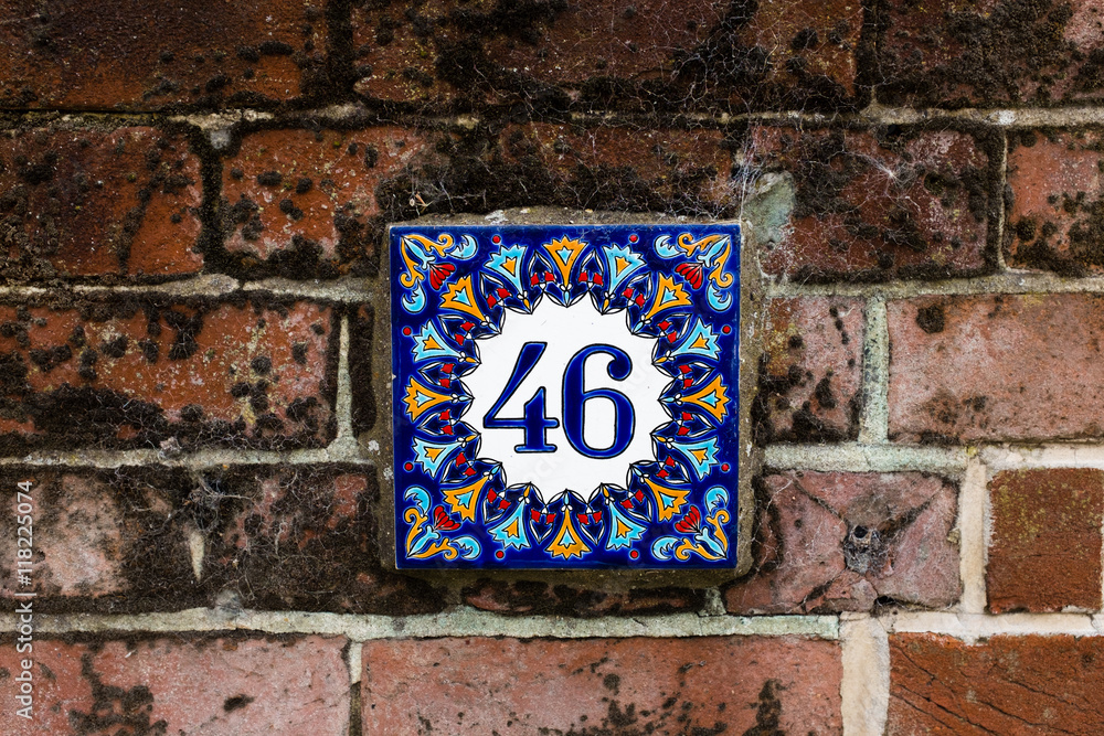 Hand-painted decorative house number tile on a brick wall – 46 (forty-six) Hand-painted decorative house number tile on a brick wall – 46 (forty-six)