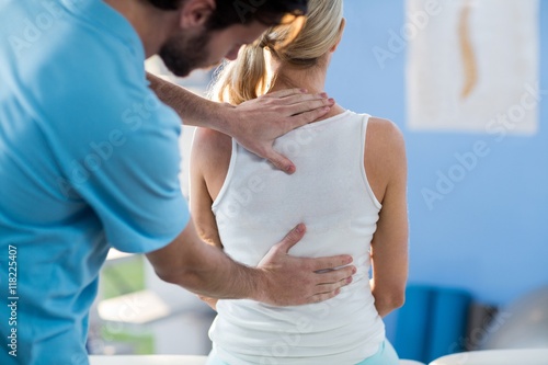 Male physiotherapist giving back massage to female patient photo