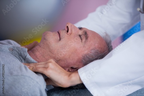 Senior man receiving shoulder massage from physiotherapist