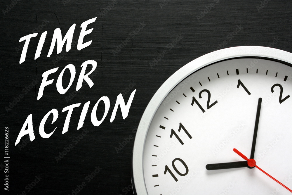 The words Time For Action written in white text on a blackboard next to a modern wall clock The words Time For Action written in white text on a blackboard next to a modern wall clock