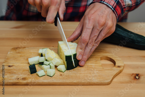 Man hands slicing fresh zucchini by ceramic knife