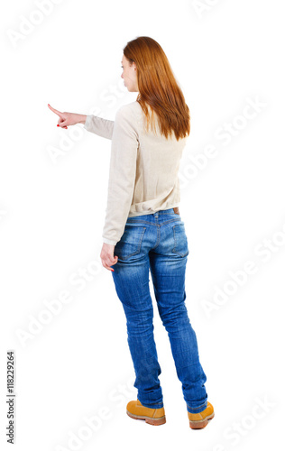 Back view of  pointing woman. beautiful girl. Rear view people collection.  backside view of person.  Isolated over white background. The girl in a white warm sweater showing with his right hand to