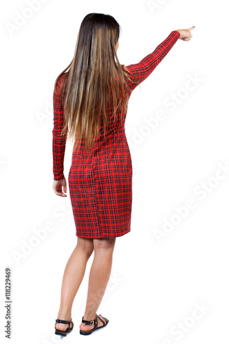 Back view of pointing woman. beautiful girl. Rear view people collection. backside view of person. Isolated over white background. The girl in red plaid dress shows an index finger upwards.