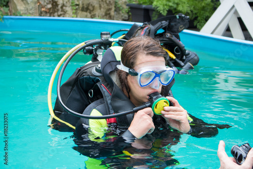 Young girl doing a scuba diving training in an outdoor pool with diving equipment mask and snorkel